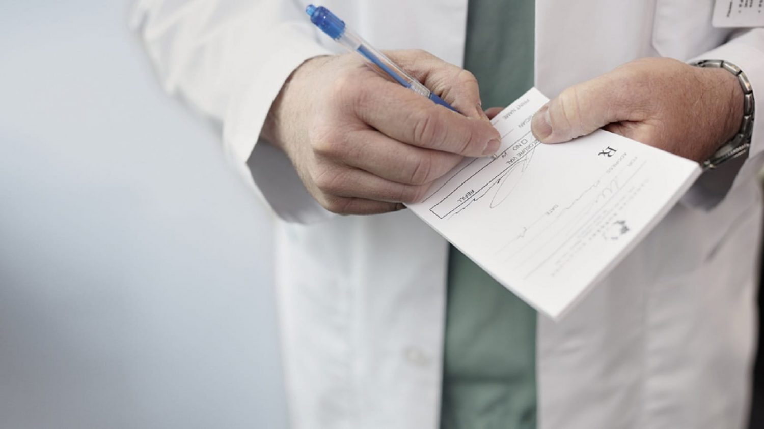 Doctor Writing A Prescription For A Patient Stock Photo