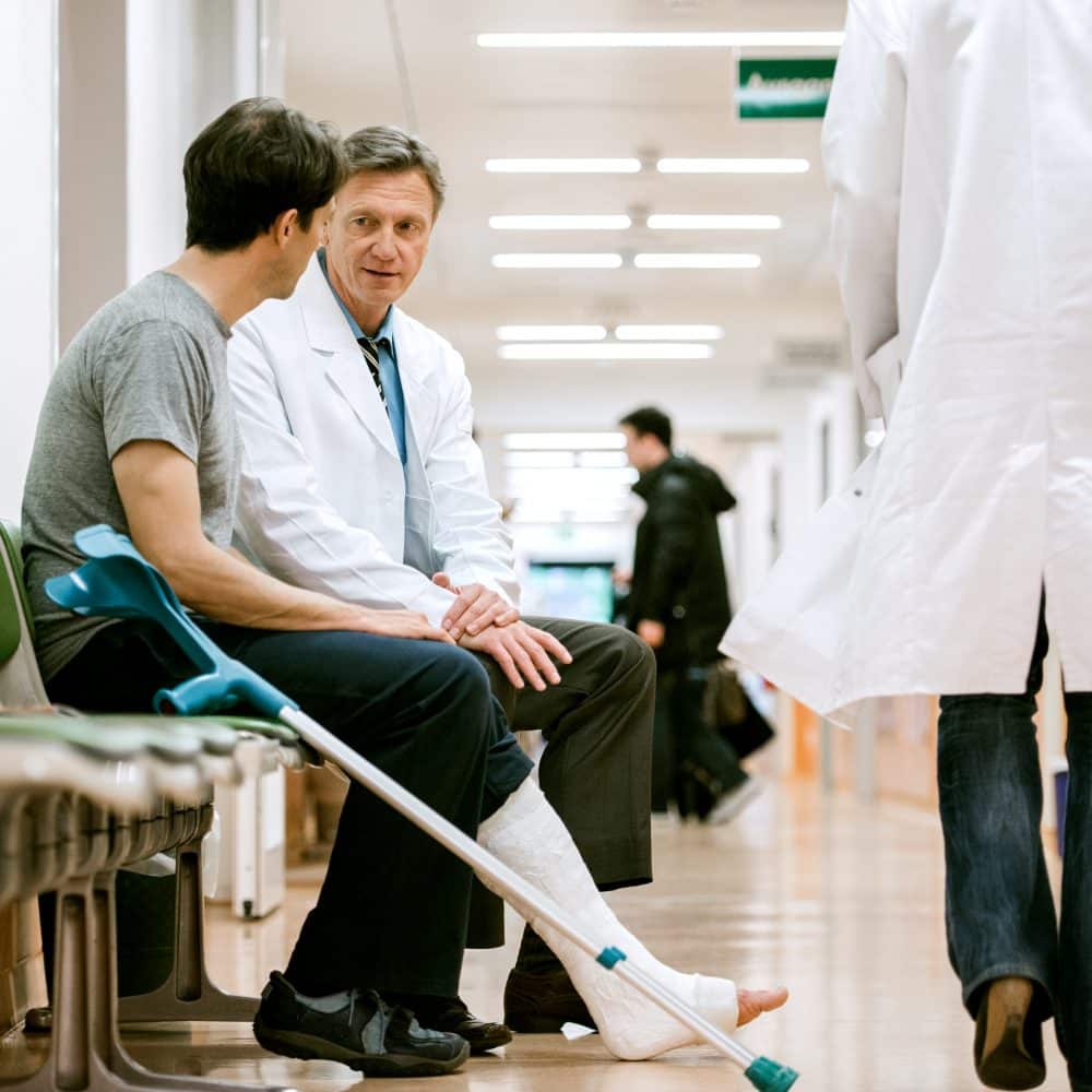 man speaking with his doctor after receiving care for his accident injury