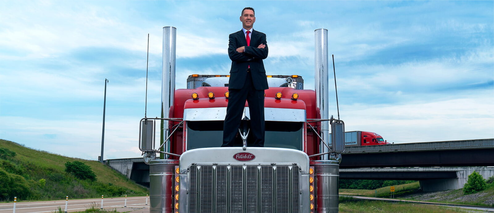 Attorney James Beardsley standing on top of a big truck, smiling with his arms crossed.
